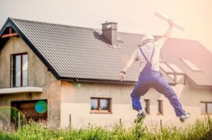 A contractor jumping excitedly while holding a plan