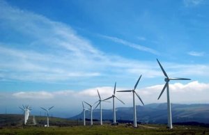 Several large wind turbines on a hilly area.