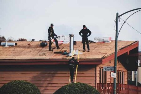 Three roofers in the middle of the roof replacement process.