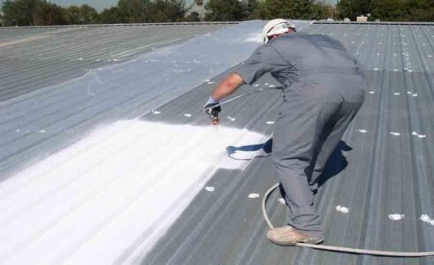 Spaying white liquid rubber onto existing roof space